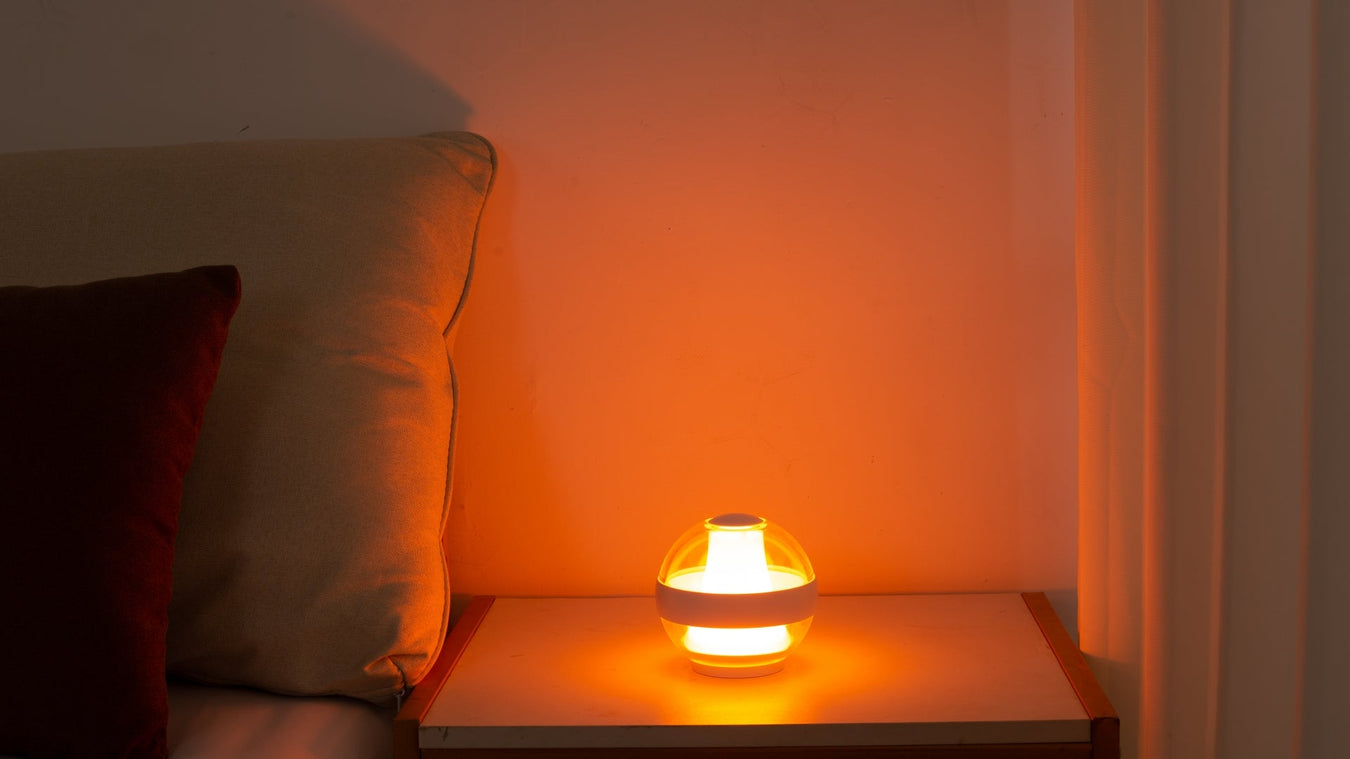 Serenity Light in Flame Warm mode on a bedside table